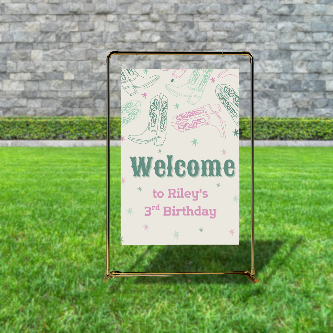 Cowgirl-themed birthday welcome sign displayed outdoors on gold stand with green grass and stone wall background. Sign features pastel cowboy boots and stars with text “Welcome to Riley’s 3rd Birthday.” Perfect western party entryway decor.