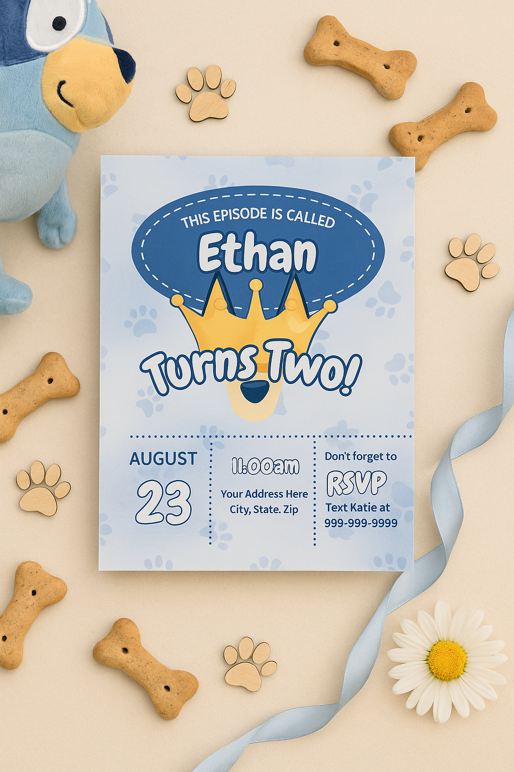 Neutral flat lay of a Bluey-inspired editable second birthday invitation for boys with a golden crown, paw prints, plush toys, bone-shaped dog biscuits, and soft blue ribbon on a beige background.
