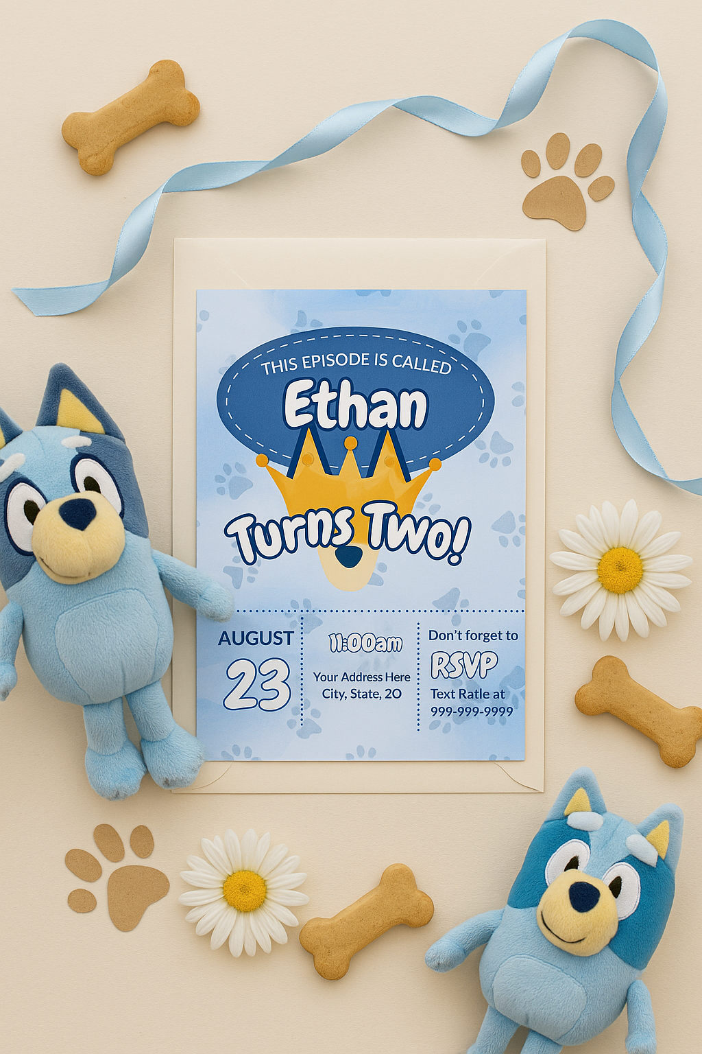 Flat lay of Bluey-inspired boy birthday invitation for a second birthday with crown, dog ears, paw prints, beige background, envelope, plush toys, ribbon, dog biscuits, and daisies.